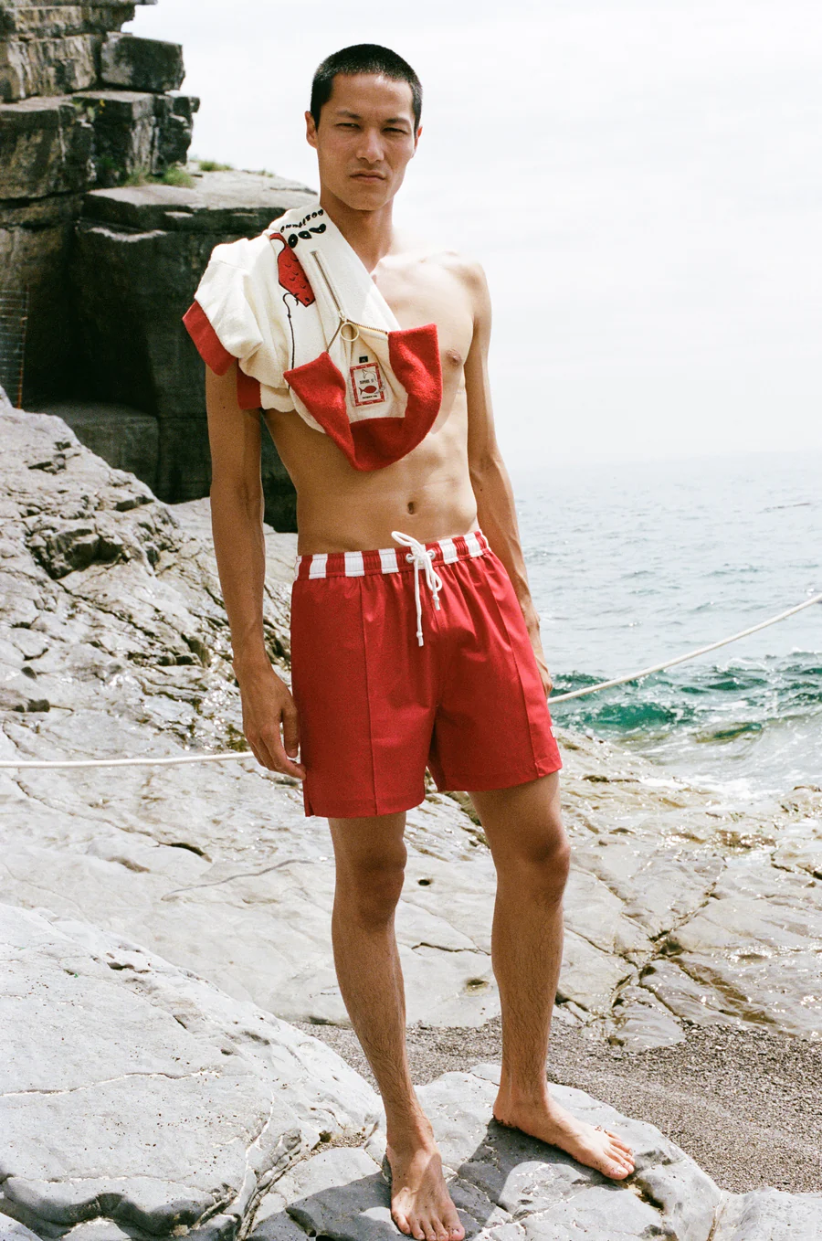male model on beach wearing red swim shorts