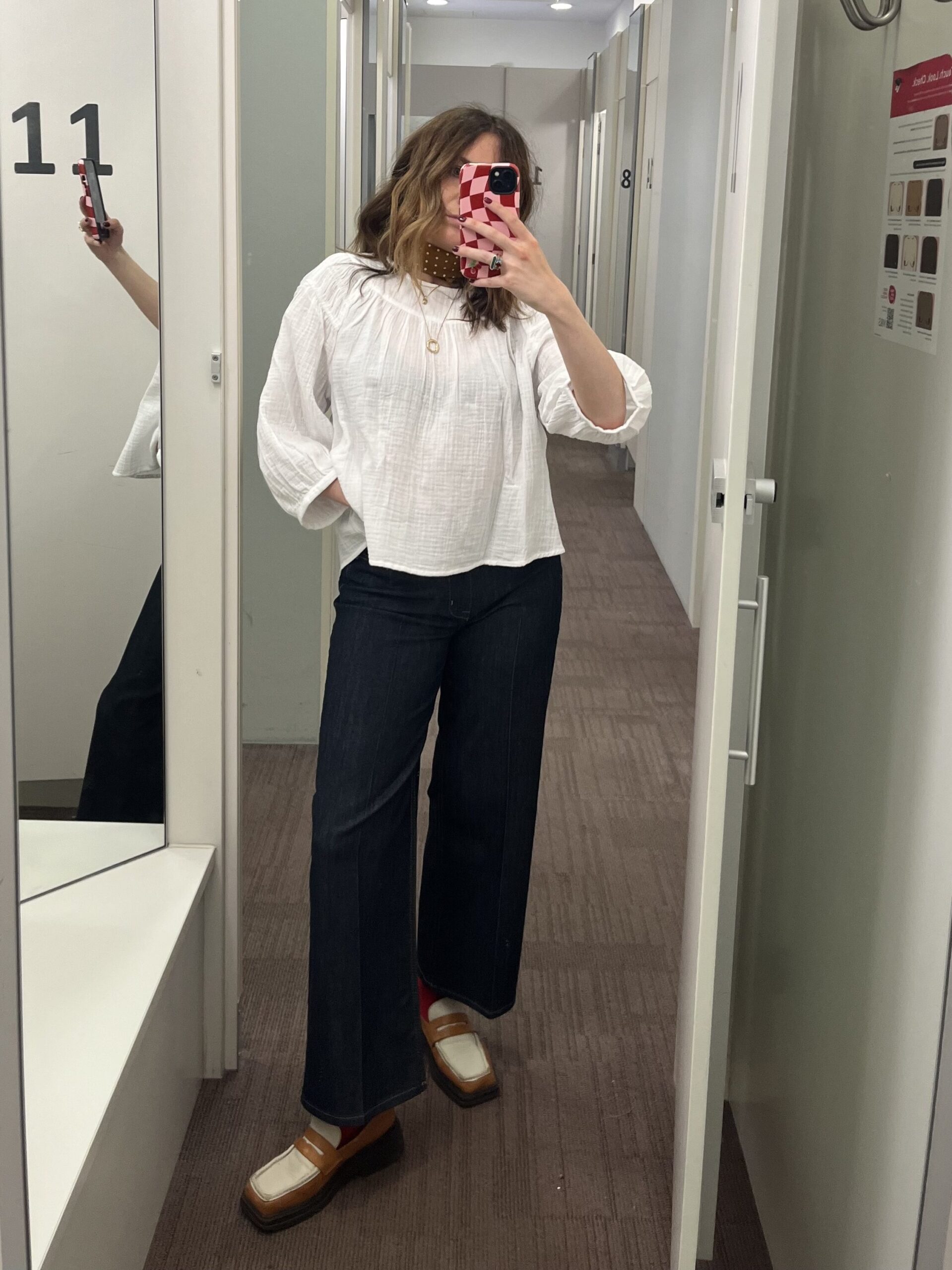 astrid in changing room wearing white cheesecloth top and dark jeans 