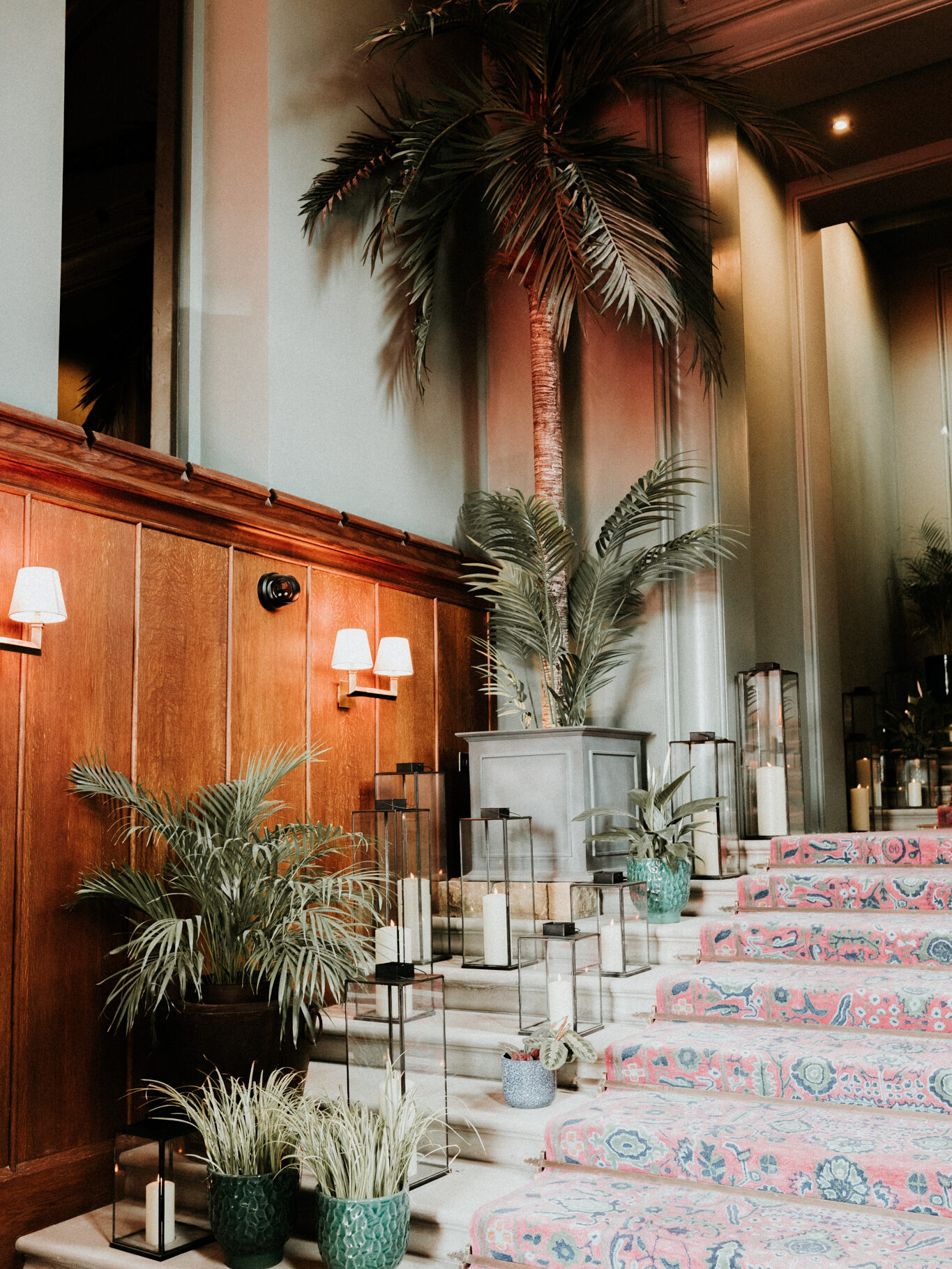 the entryway at mar hall with staricase, wood panelled walls and palm trees 