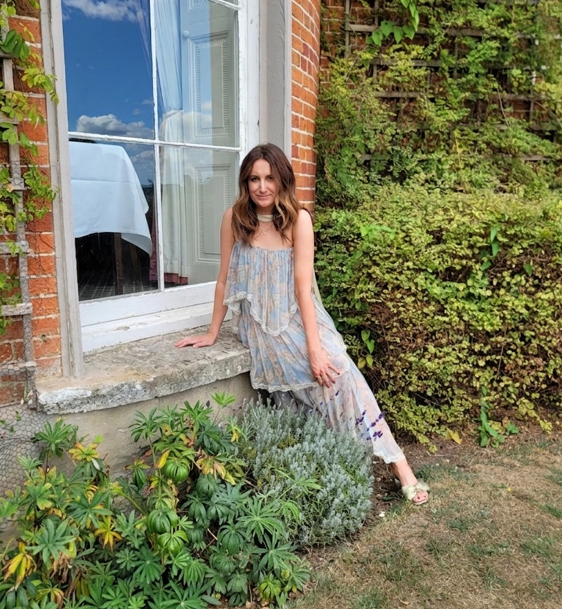 Astrid Carter wearing long floral dress witting on window at wedding