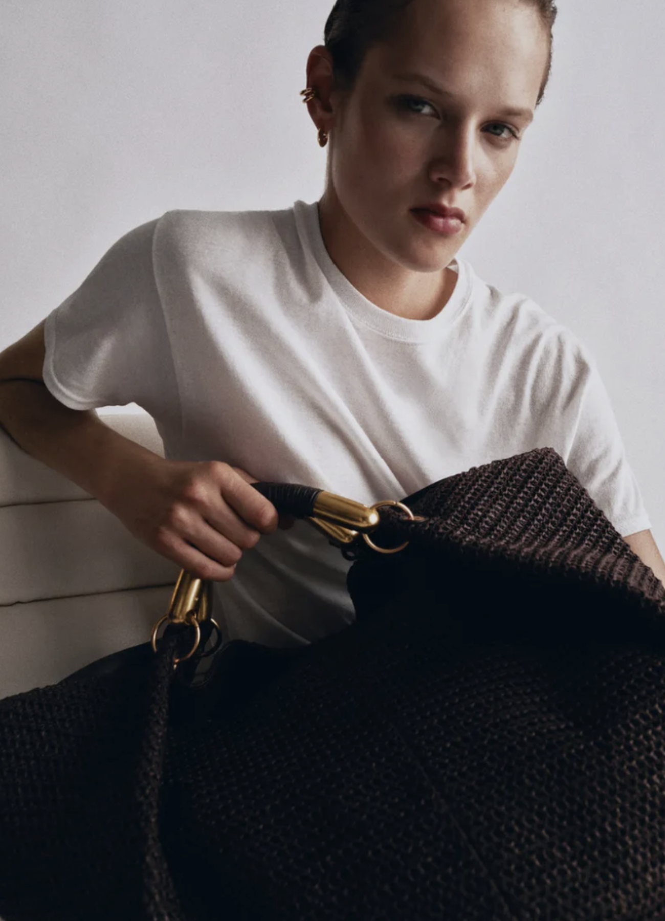 Model in white holding a brown tote bag