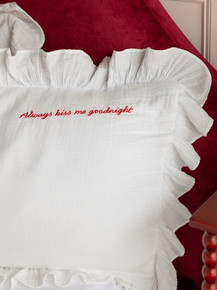 White ruffled Rockett St George pillowcase embroidered with the red text Always kiss me goodnight.